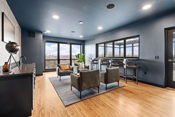 a living room with couches and chairs and a bar with windows